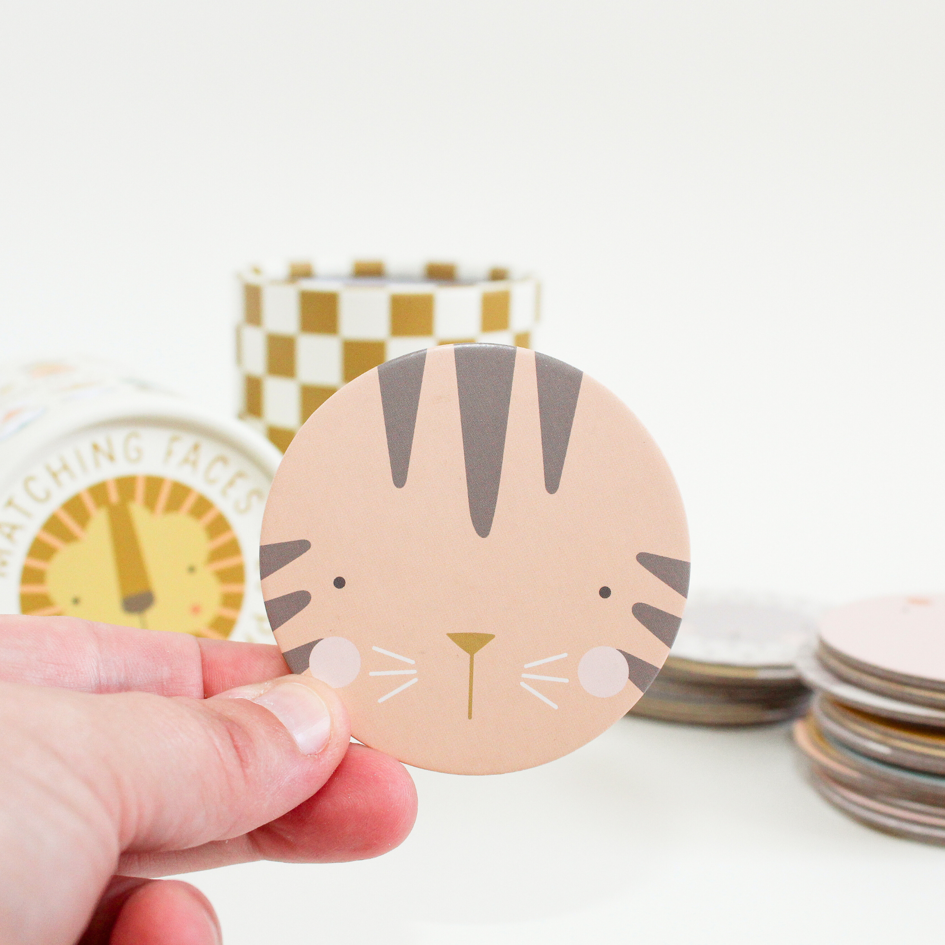 close up of a hand holding the circular tiger face matching piece with packaging in the background.