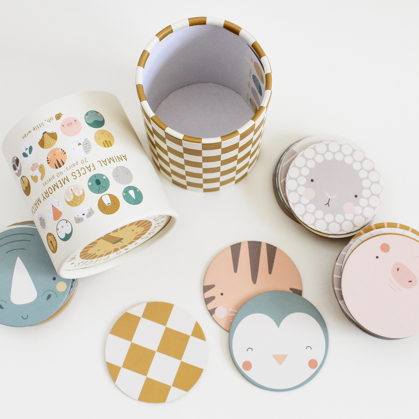 a top down view shows the matching game spread out, including the top lid on it’s side, the tube base standing up, and a scattering of pieces. face-up pieces shown, from left to right, top to bottom, are: rhino, sheep, tiger, pig and penguin. a face-down, yellow and white checkered piece.