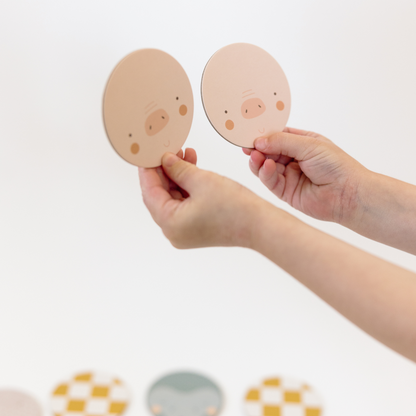 two child’s hands hold a matching pair of cute circular pig faces.