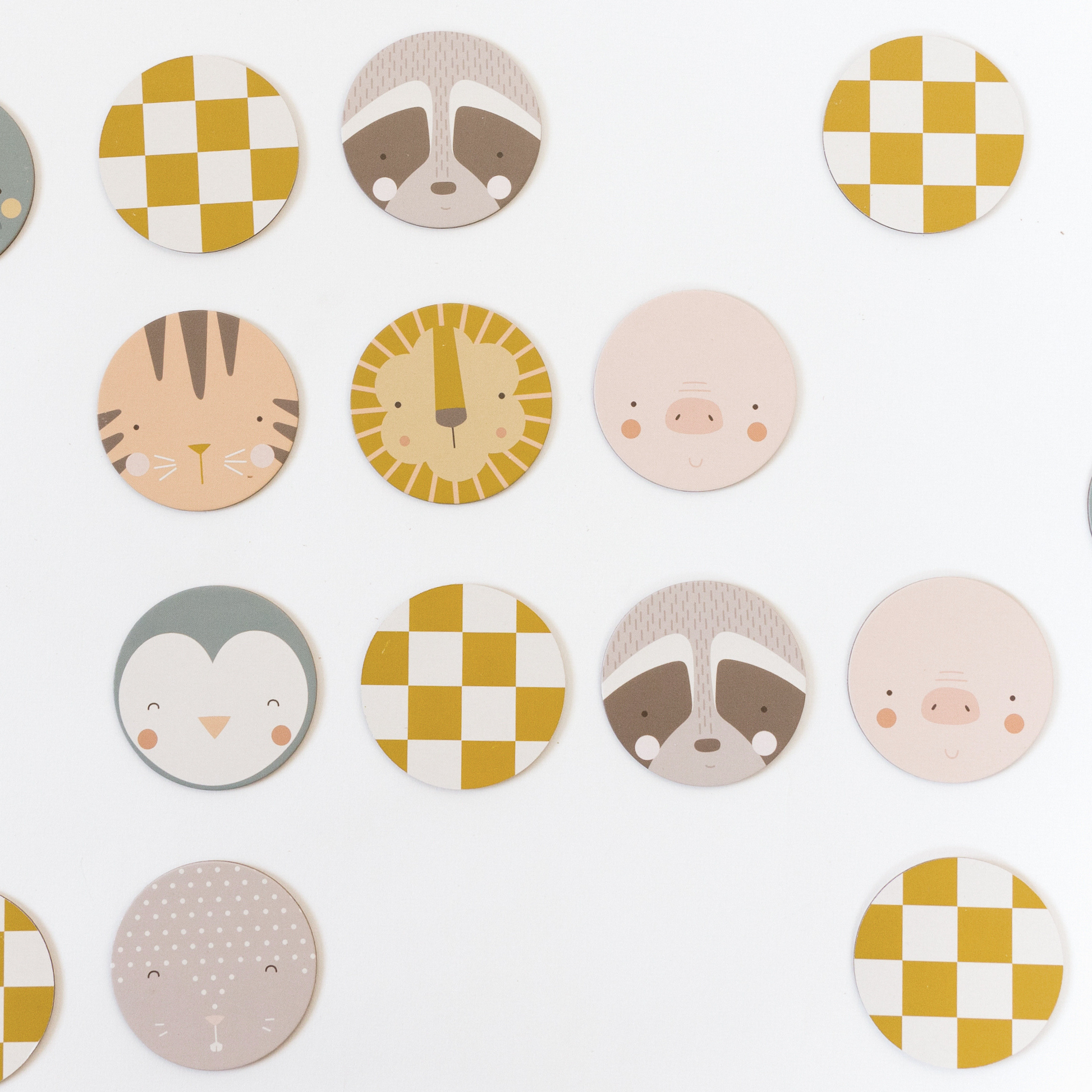 a scattering of circular matching pieces are shown, some face-up, showing animals, some face-down showing yellow and white checks. face-up animals shown from top to bottom, left to right are: raccoon, tiger, lion, pig, penguin, raccoon, pig, rabbit.