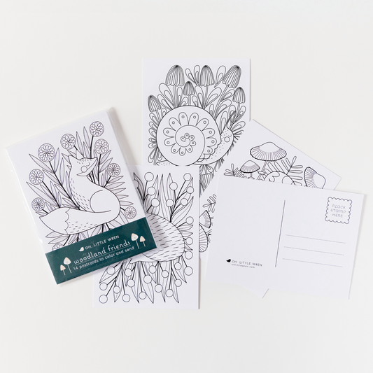 a packing of woodland animal coloring postcards are spread out on a white background. shown, from left to right are a fox with flowers, hedgehog with flowers, snail with mushrooms, racoon with mushrooms, and the back of the card showing lines for sending as a postcard.
