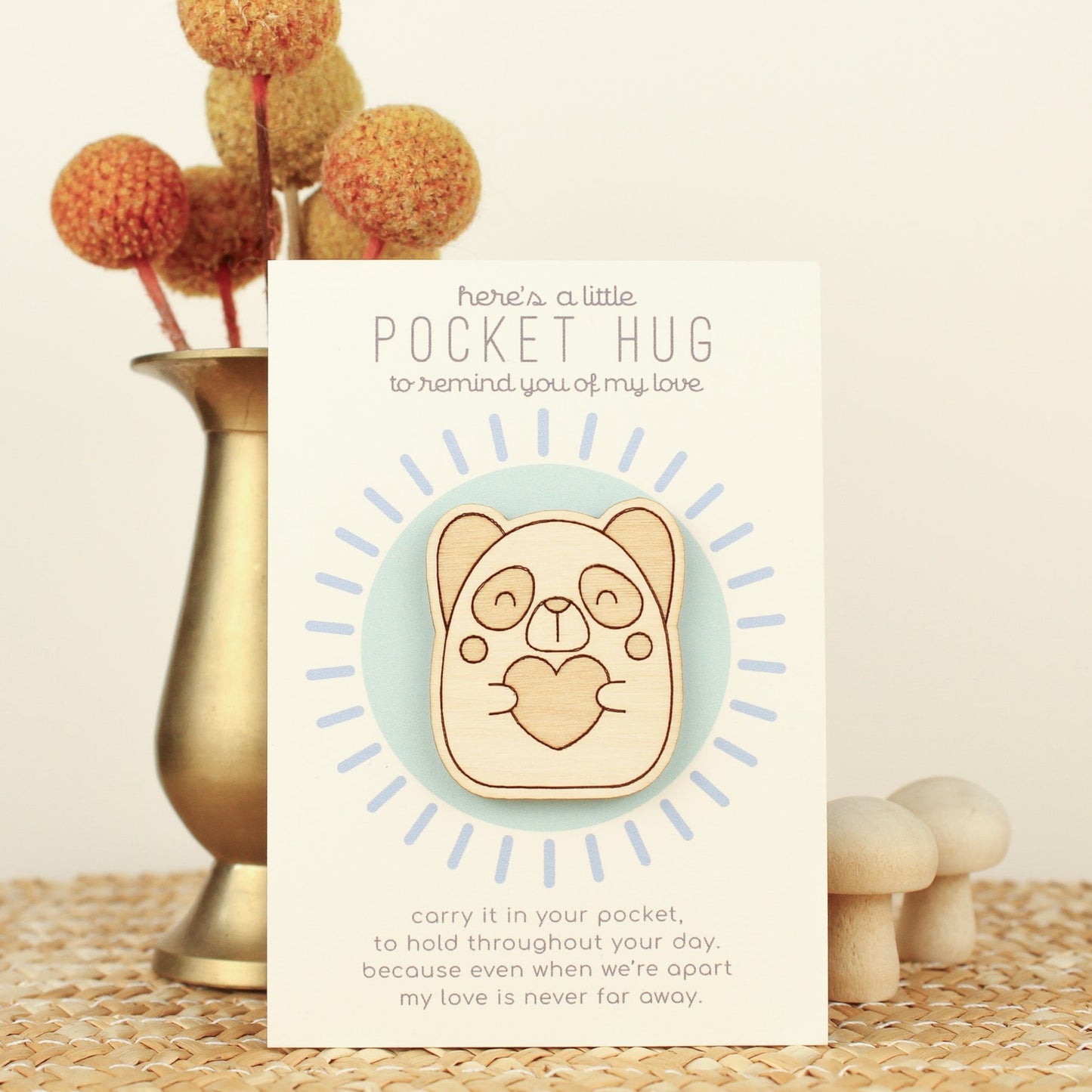 wooden panda pocket hug is shown on its backer card propped up against a brass flower vase. card reads 'here's a little pocket hug to remind you of my love' and at the bottom 'carry it in your pocket, to hold throughout the day, because even when we're apart my love is never far away.'